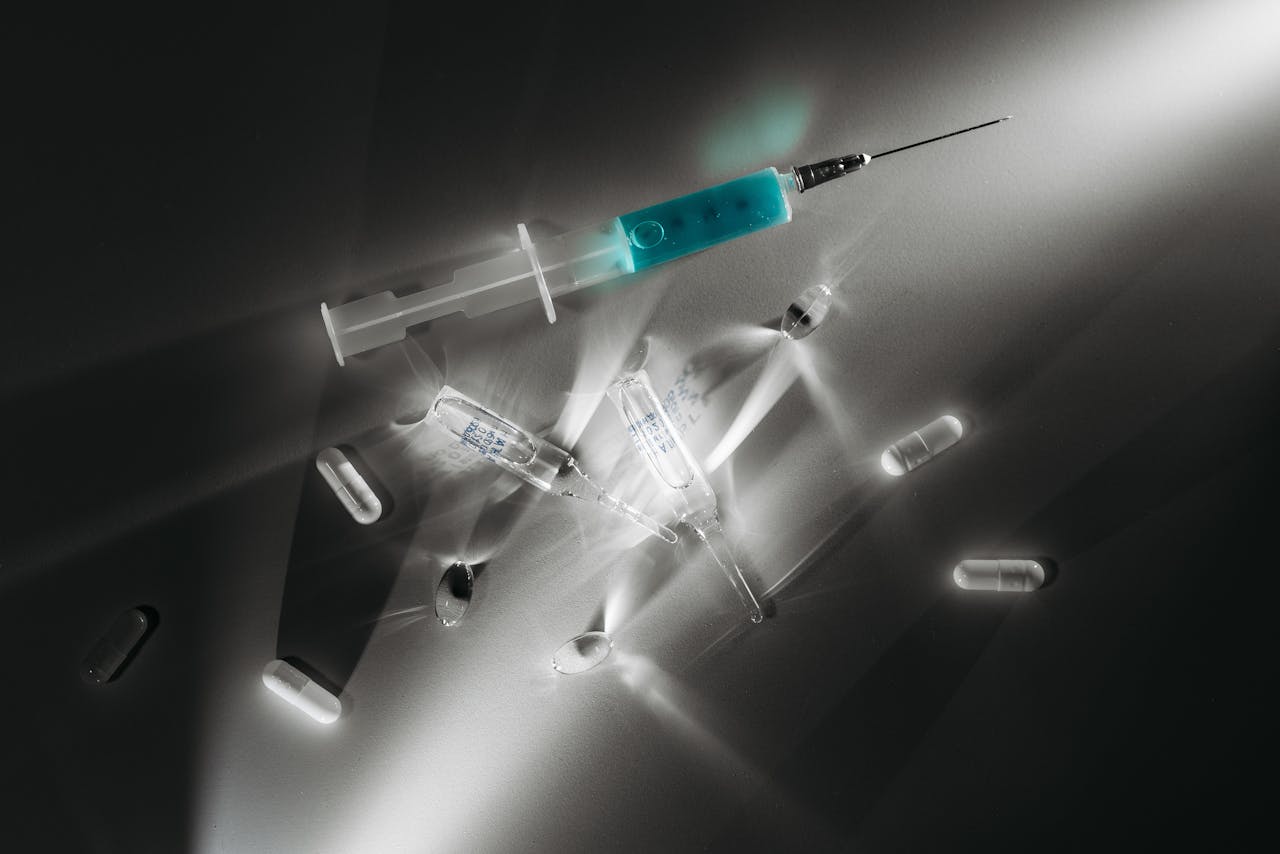 High contrast image of medical supplies, including a syringe and capsules, in a monochrome setting.