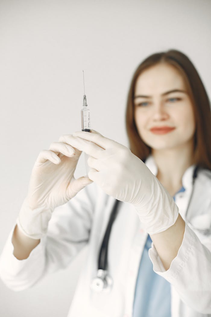 Smiling female doctor with gloves preparing a syringe for vaccination.