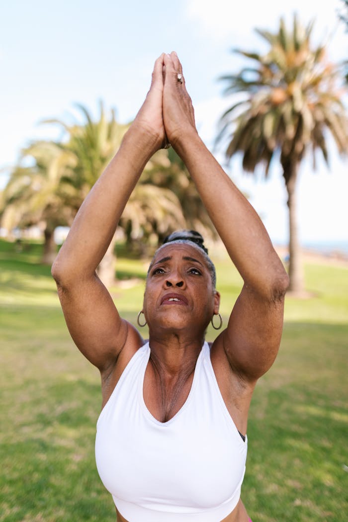 Elderly woman practicing yoga outdoors, embracing wellness and mental health.